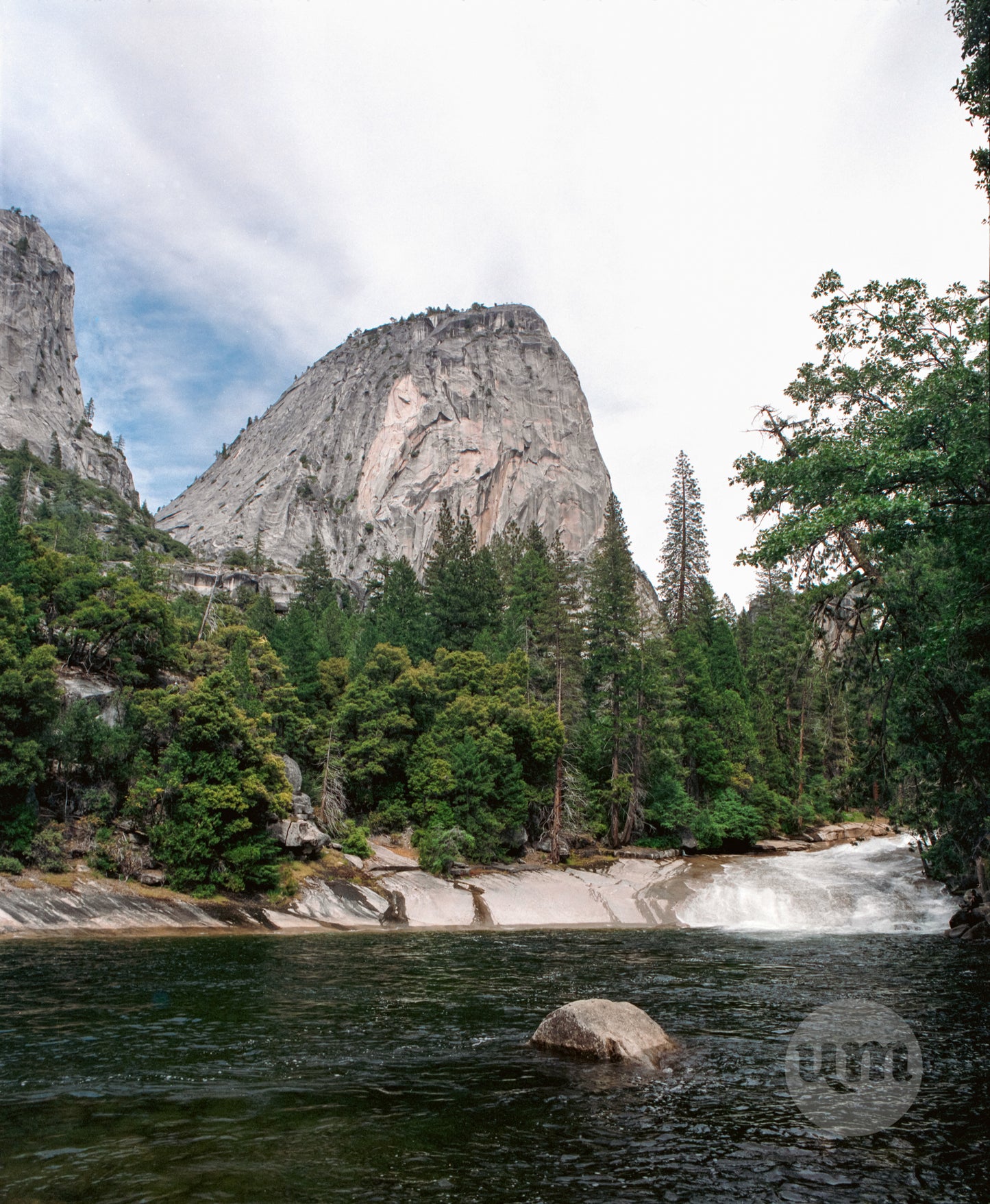 Scenic view of a mountain range with trees and a river, featuring the Parque logo.