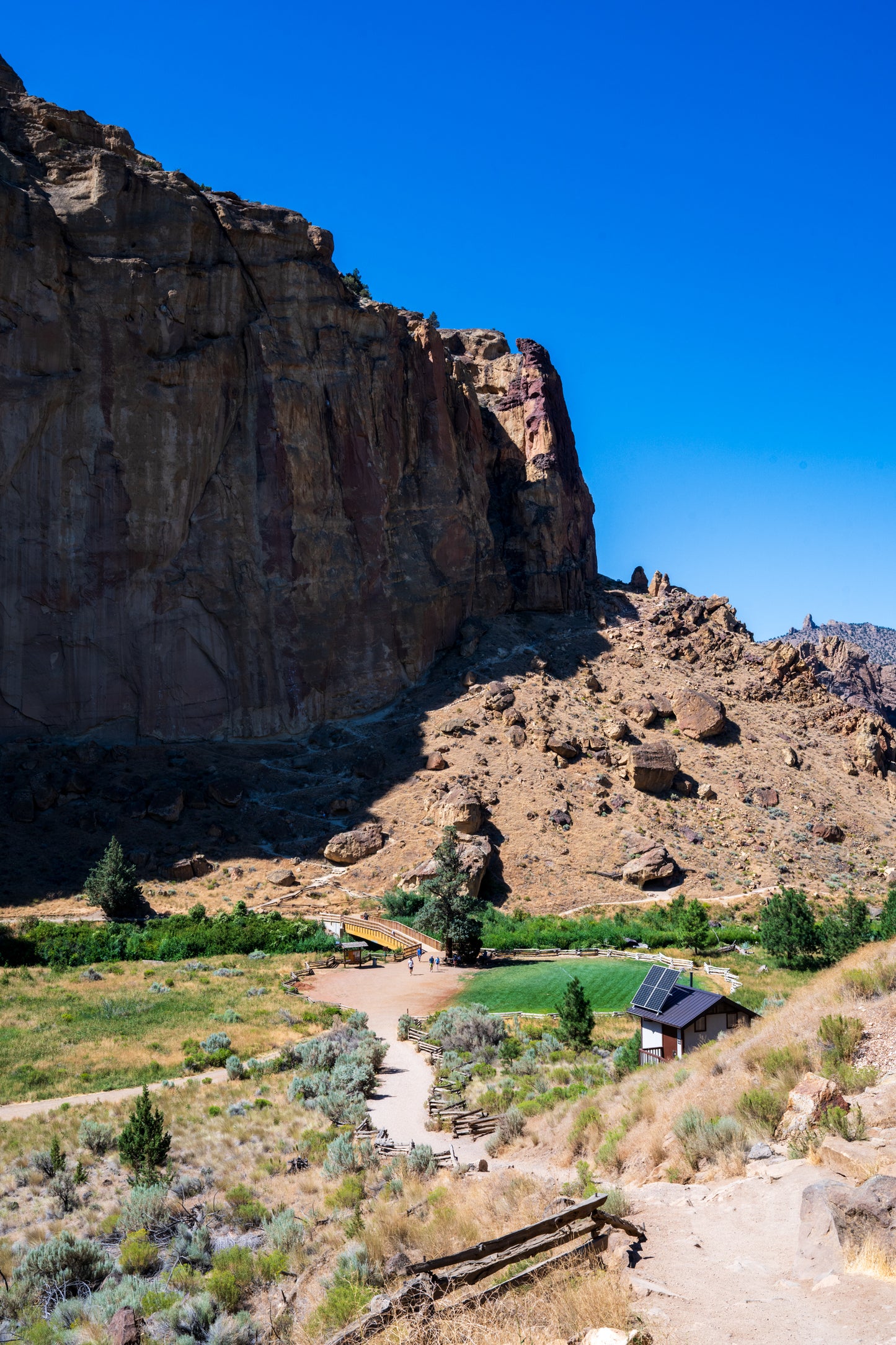 Rural landscape with a small building on a hillside under a clear blue sky.