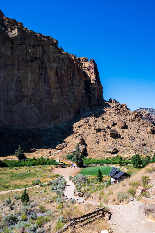 Rural landscape with a small building on a hillside under a clear blue sky.