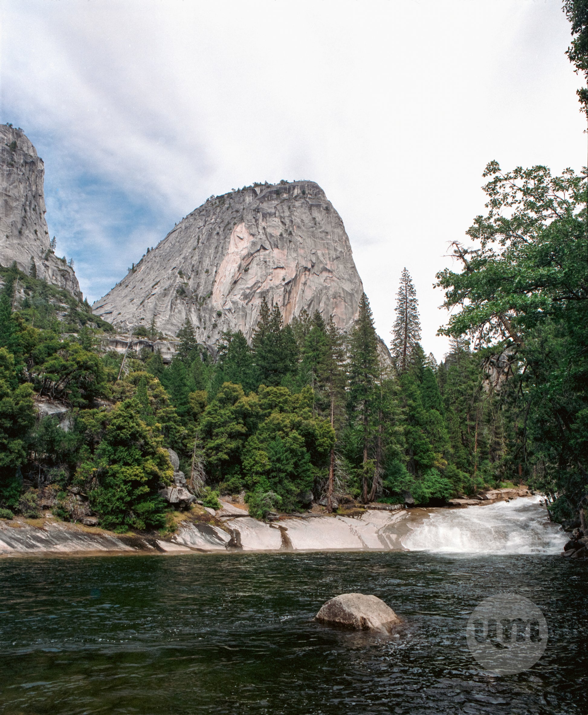 Scenic view of a mountain range with trees and a river, featuring the Parque logo.