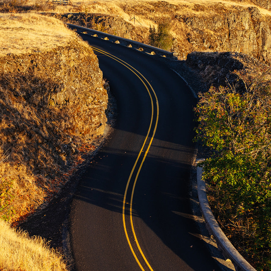 Winding road with a yellow center line through a scenic landscape.