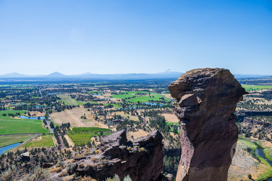 Scenic view from a rocky outcrop overlooking a valley with fields and mountains.