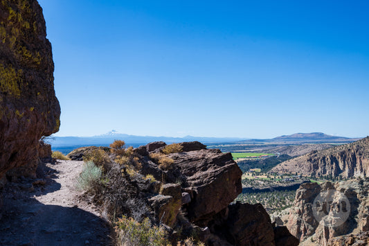 Scenic view from a rocky outcrop with a clear blue sky and distant landscape.