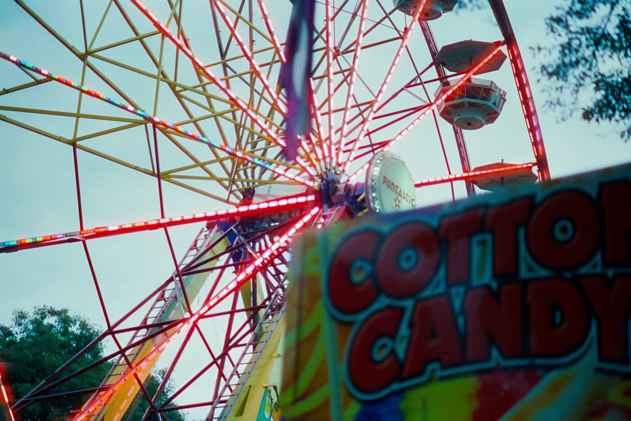 Ferris wheel with a cotton candy stand in the foreground against a blue sky.